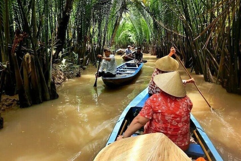 People paddling in a narrow waterway surrounded by tall trees. 2