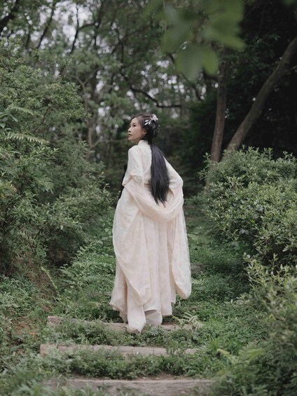 A person in traditional attire walking on a stone pathway surrounded by greenery. 5