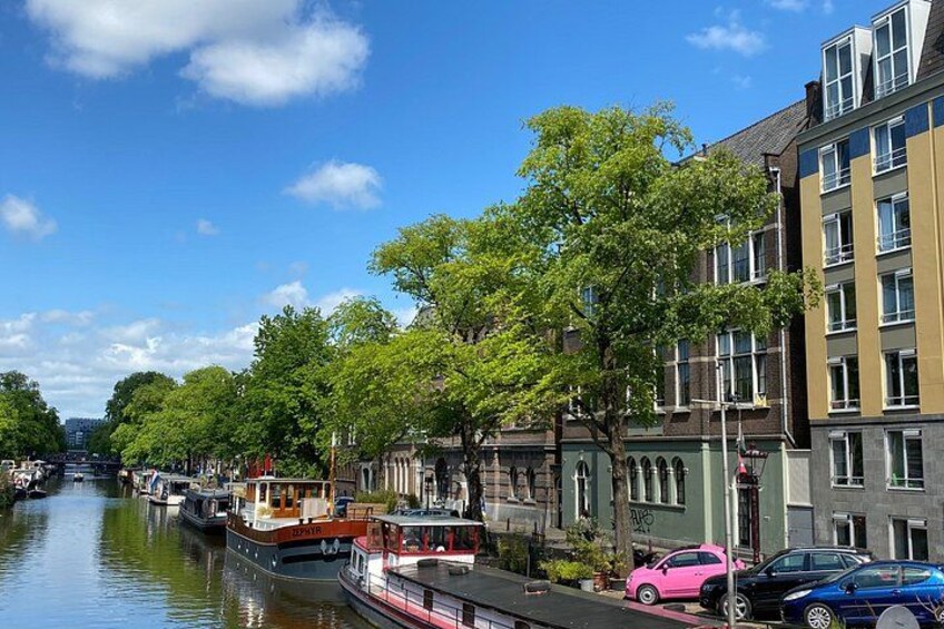 A canal with boats, a pink car, and buildings along the water. 3