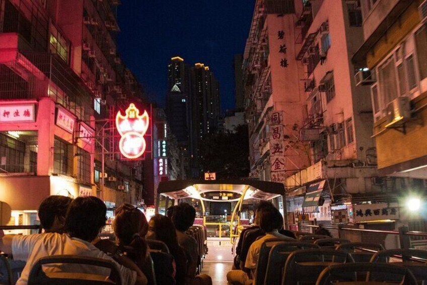 A nighttime street scene with a bus, illuminated signs, and high-rise buildings. 5