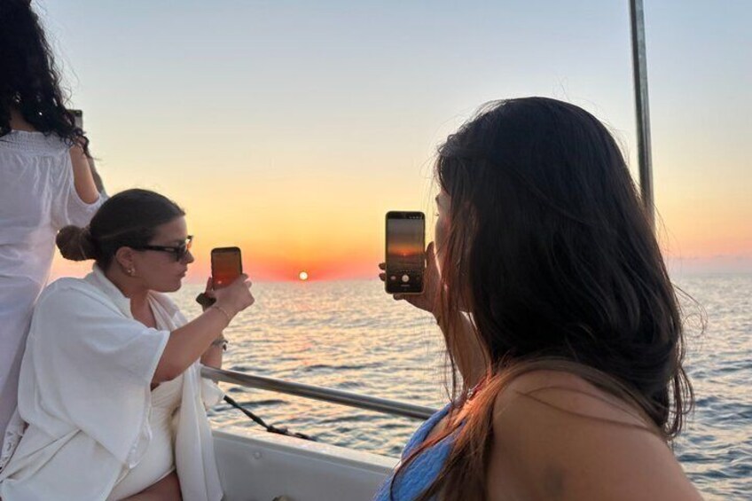 A sunset over the ocean with people taking photos. 5