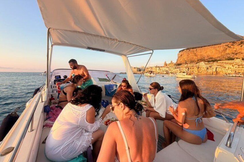 A group of people on a boat near a coastal town with buildings and cliffs. 3