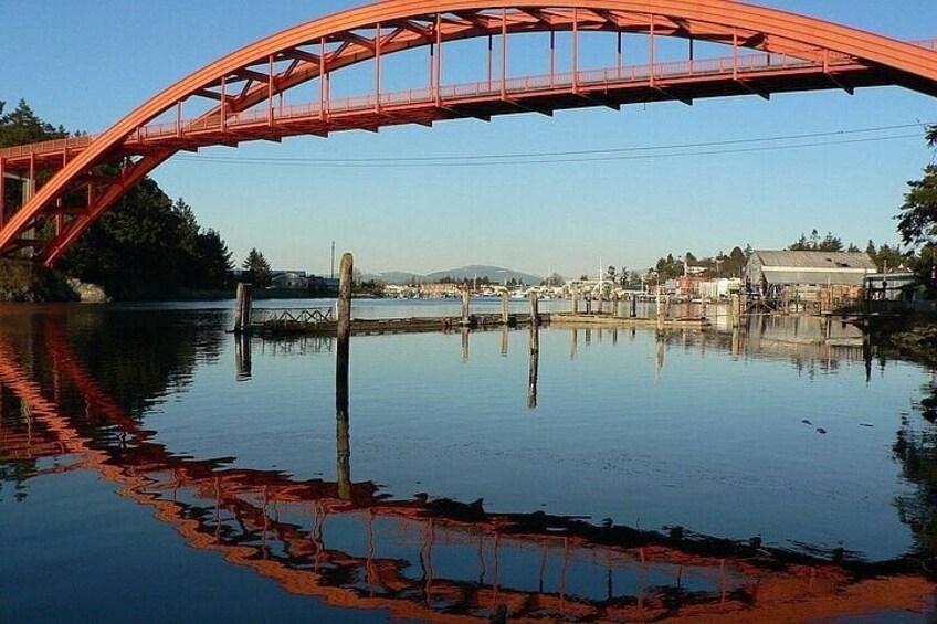 A red bridge over calm water with reflections, a dock, and buildings in the background. 4