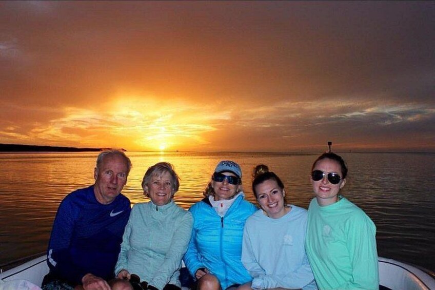 Un grupo de personas en un barco con un atardecer de fondo. 2