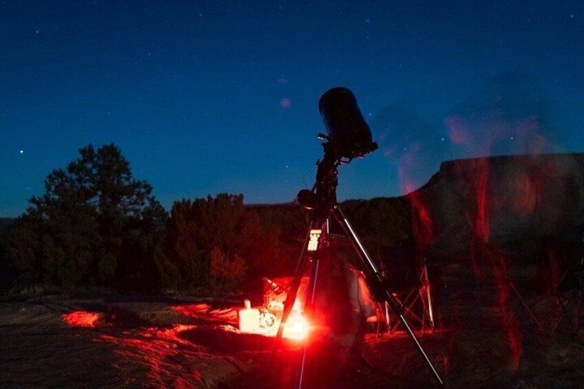 A telescope on a tripod with a bright light source nearby. 3