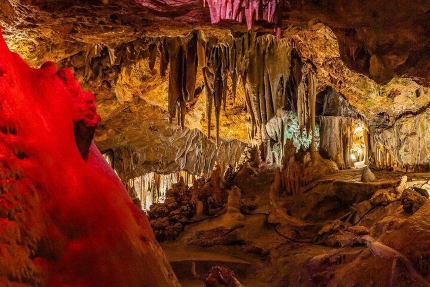 A cave with stalactites and stalagmites, illuminated by artificial lighting. 1