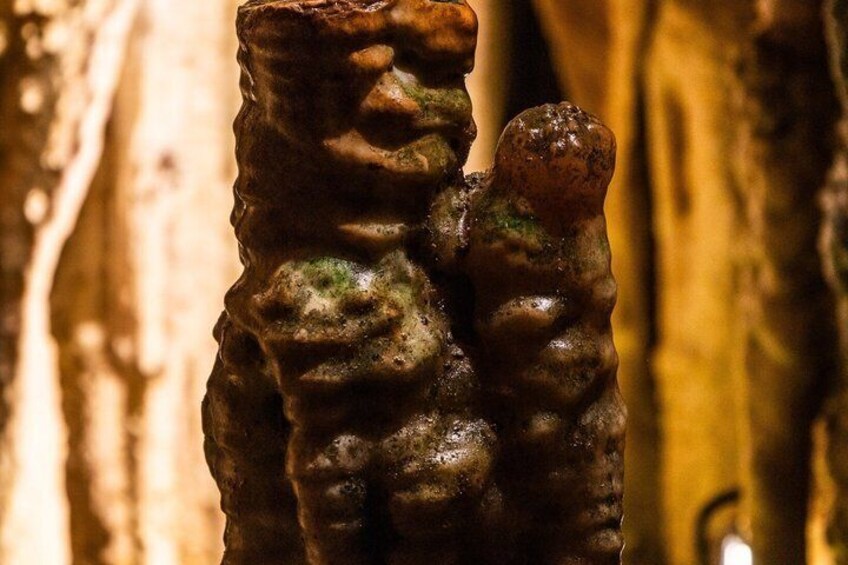 A textured sculpture resembling a bear with a human figure, set against a blurred background. 2