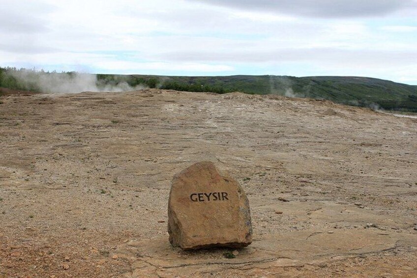 A large rock with 'GEYSIR' carved on it in a barren landscape. 5