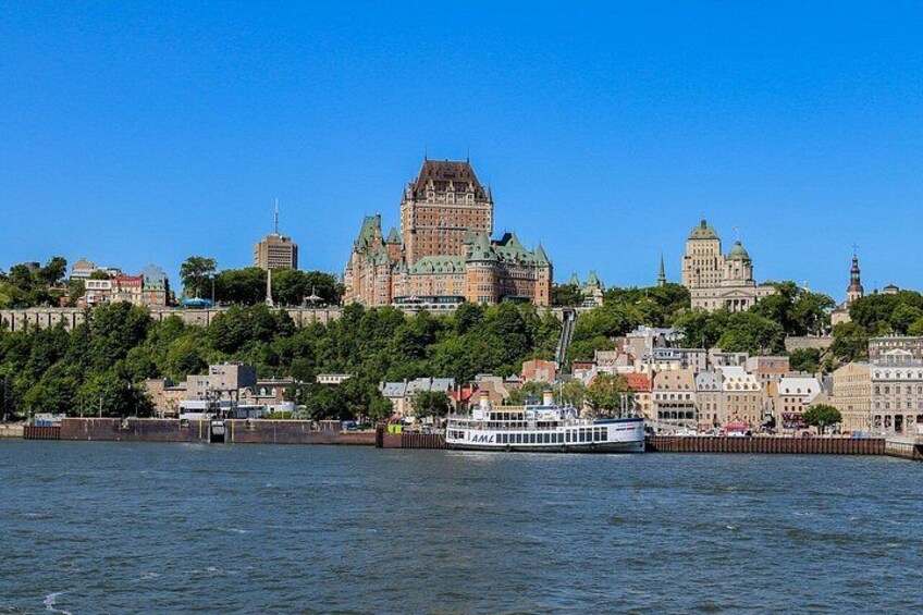 A river with a boat, a city skyline with historic buildings, and a clear blue sky. 2