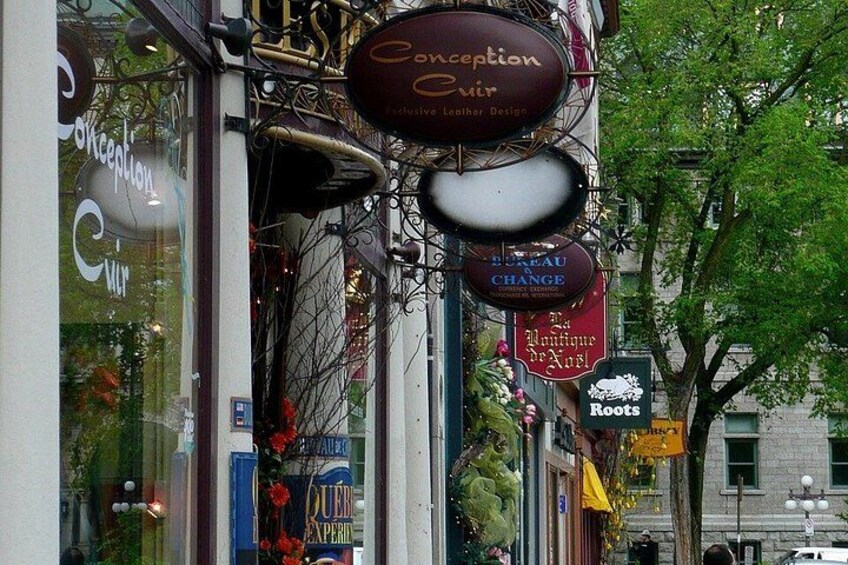 Storefronts with hanging signs, including 'Conception Cuir' and 'Roots.' 3