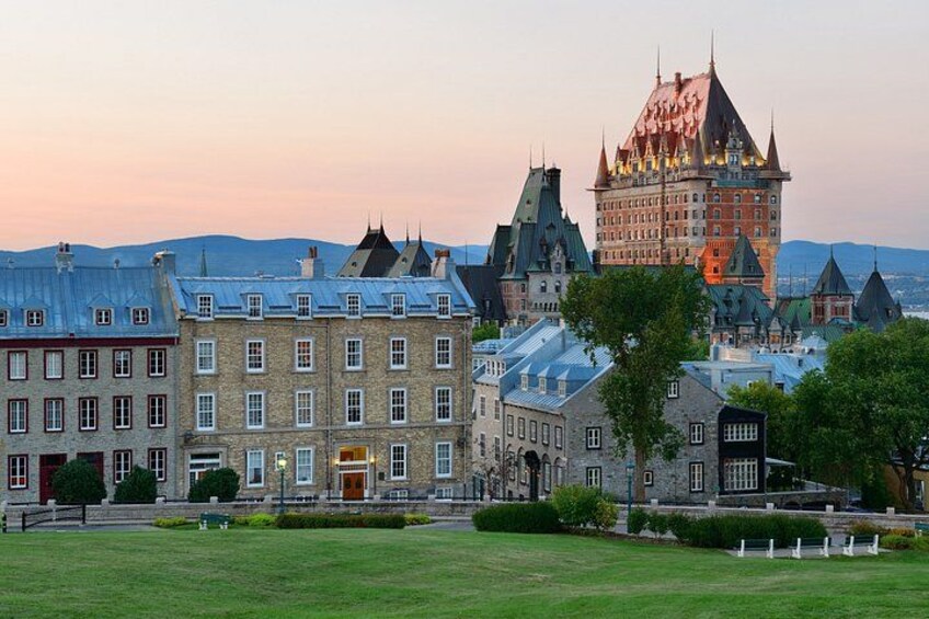 A historic building complex with multiple towers and a large central building, surrounded by a well-maintained lawn and trees. 5