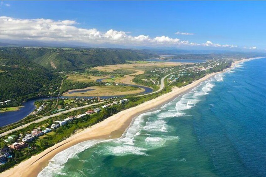 A coastal landscape with a beach, ocean, and a winding road along the coast. 2