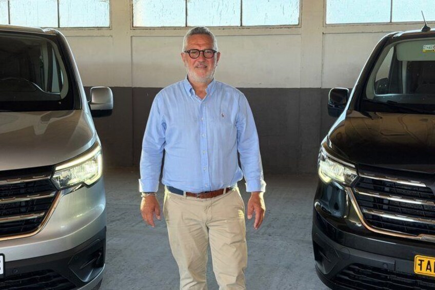 A man standing between two SUVs in a garage. 3
