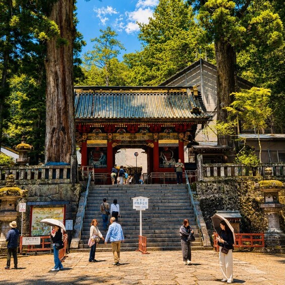 A traditional Japanese temple with a tiled roof, surrounded by large trees and a stone staircase leading up to the entrance. 3