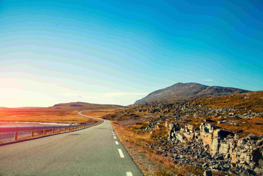 A winding road through a rocky landscape with a mountain in the distance. 4