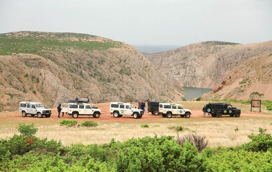A group of off-road vehicles parked on a dirt road in a mountainous area with sparse vegetation. 2