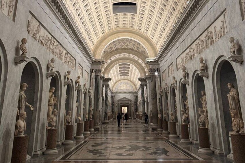 A grand hallway with statues, columns, and a high ceiling. 4