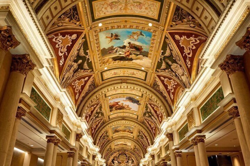 A grand hall with ornate ceiling frescoes and columns. 1