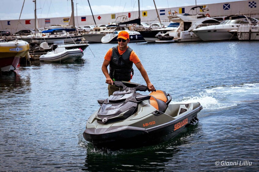 A man riding a Sea-Doo jet ski on calm water with several boats docked in the background. 1