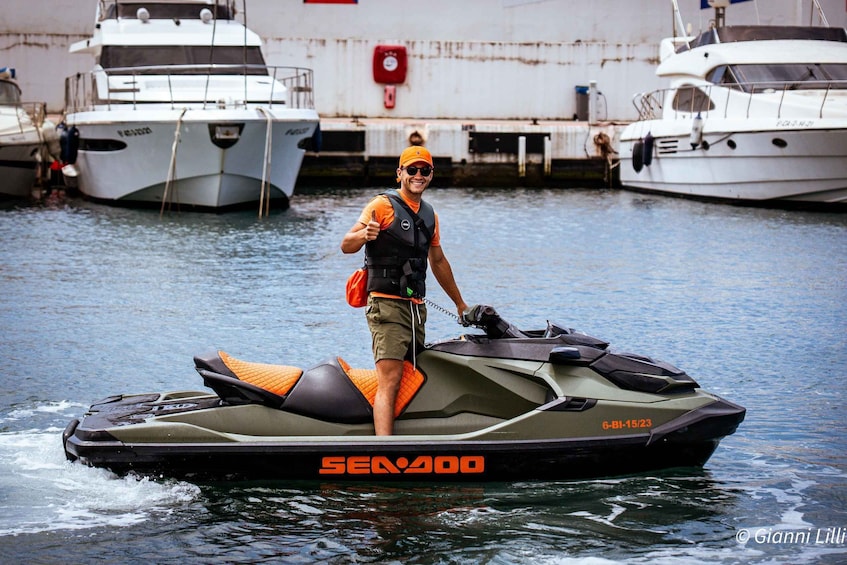 A person on a Sea-Doo jet ski with a number 6-BI-15/23, near docked boats. 3