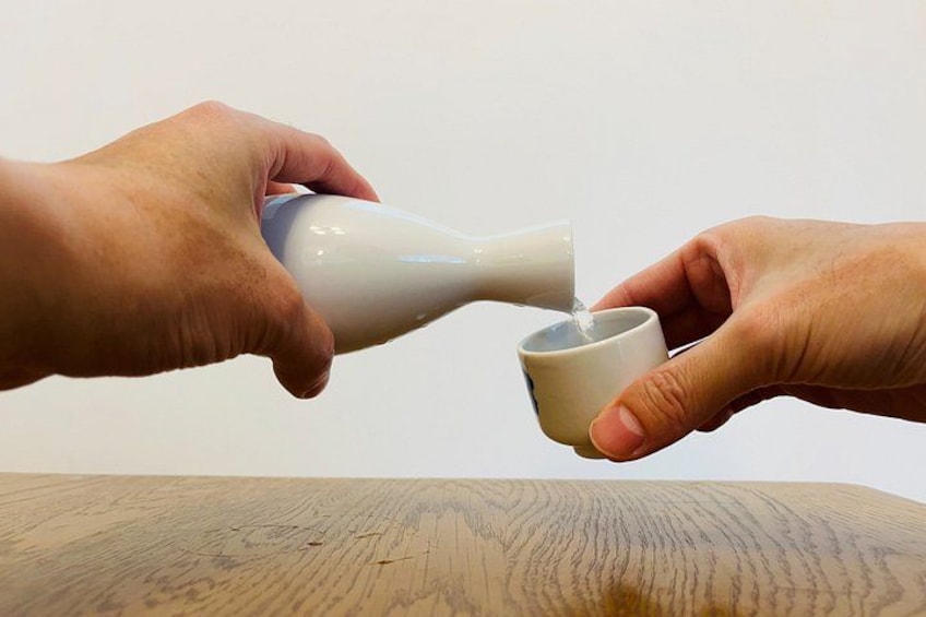 Two hands pouring a white liquid from a bottle into a cup. 5