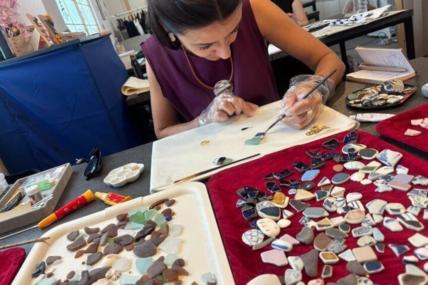 A person painting on a canvas with various stones and tools on the table. 4