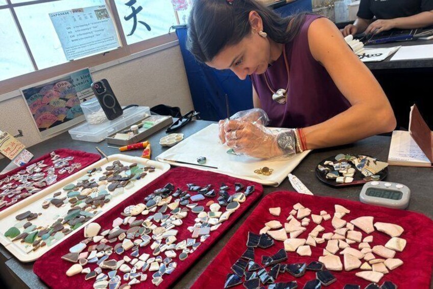 A person working at a table with various stones and jewelry items. 5