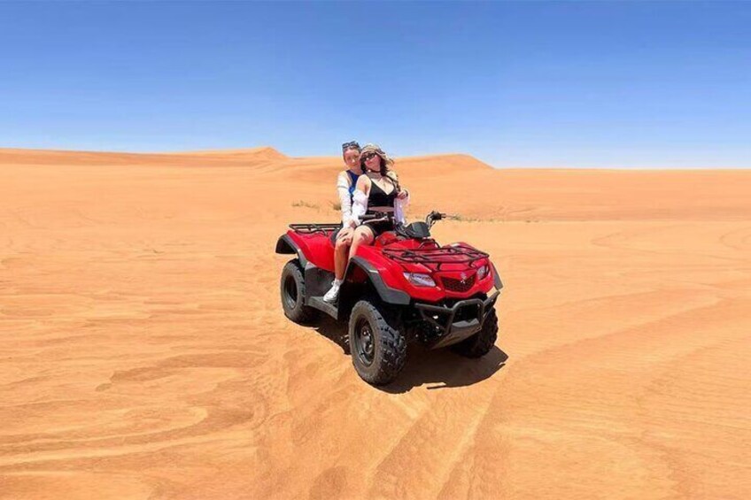 A red quad bike in a desert with sand dunes in the background. 1