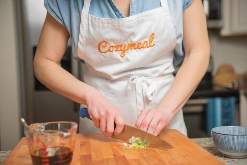 A person chopping vegetables on a wooden cutting board. 1