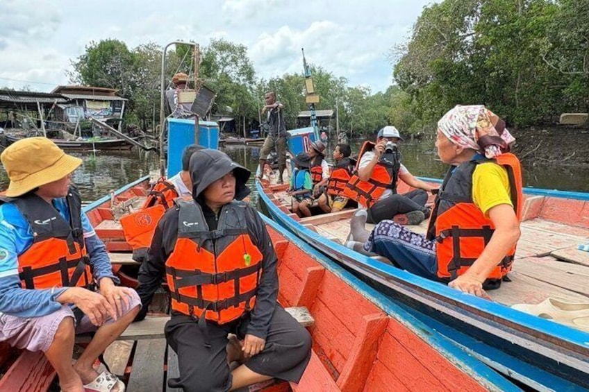 People on a boat wearing life jackets, a river, and some trees in the background. 2