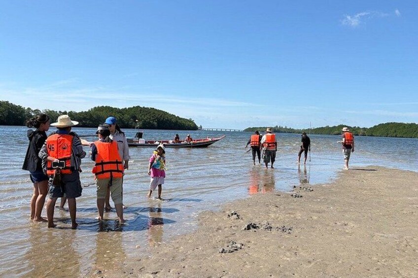 People wearing life jackets on a beach by a lake. 3