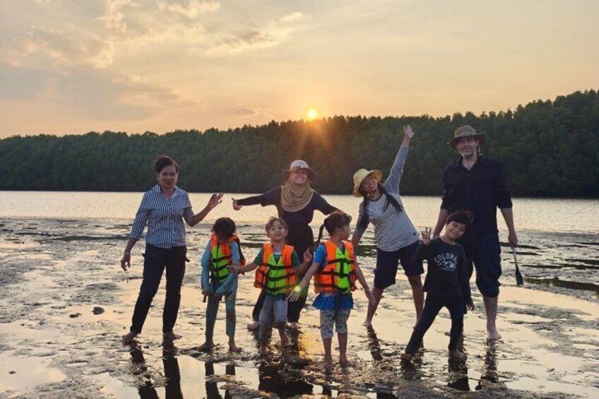A group of people on a lakeside at sunset. 1