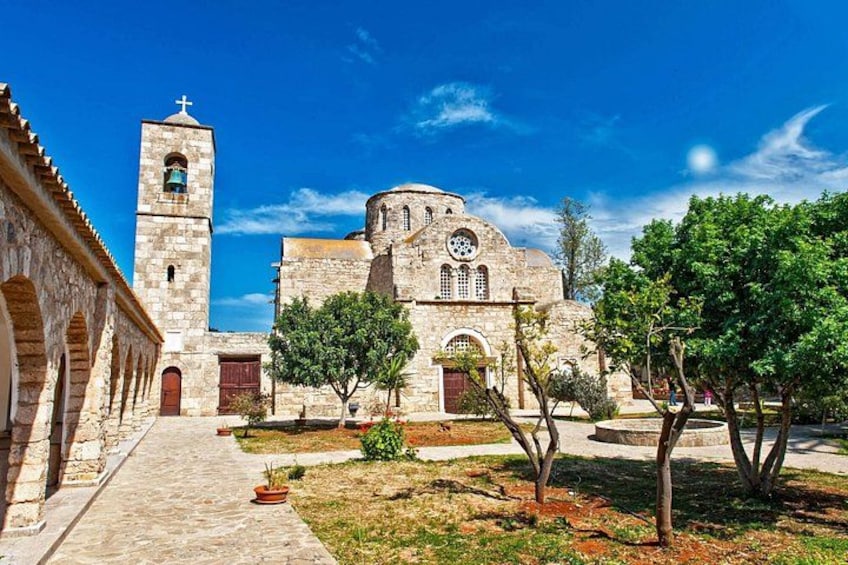 A historic church with a bell tower, arched windows, and a courtyard with trees and a pathway. 2