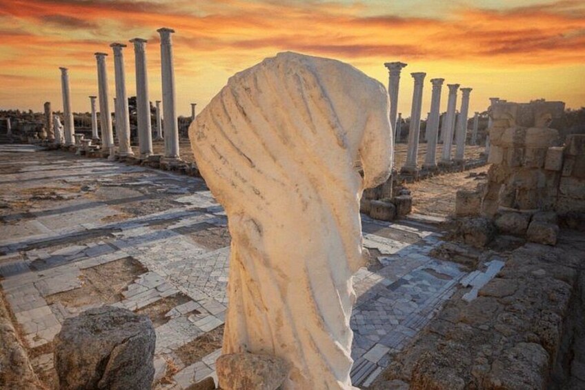 Ancient ruins with columns and a large stone structure. 1