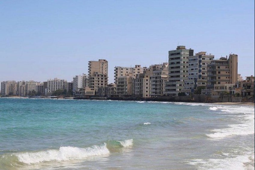 A coastal cityscape with high-rise buildings and a clear blue sea. 5