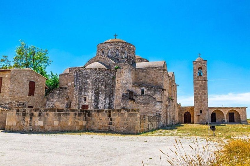 A historic stone church with a bell tower, surrounded by a low stone wall and a clear sky. 3