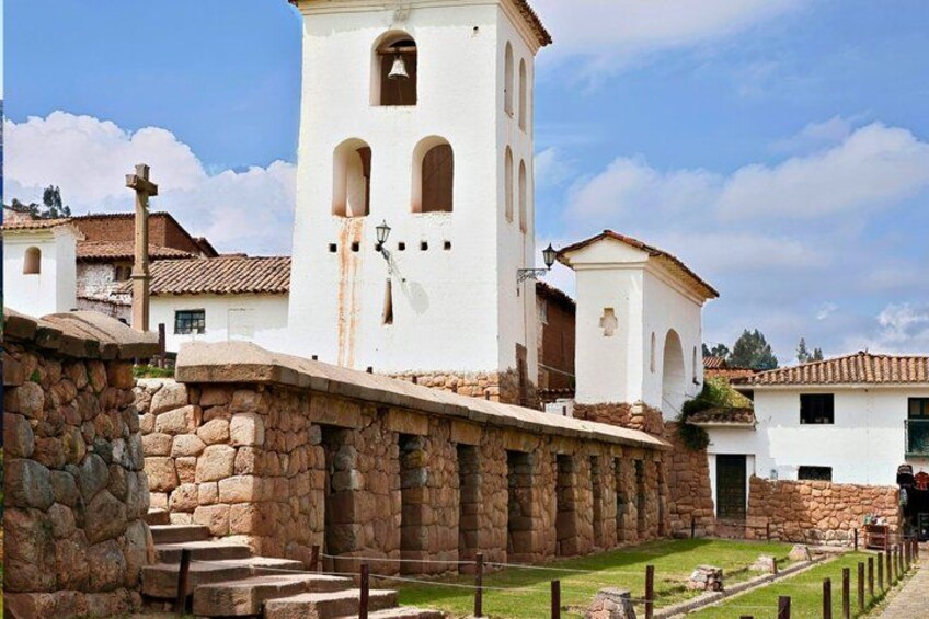 A white church with a bell tower, stone steps, and a stone wall. 2