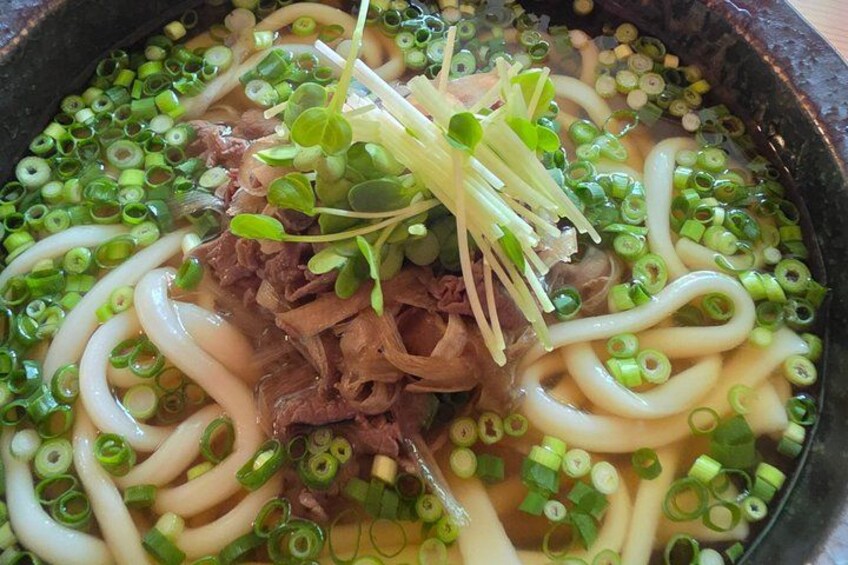 A bowl of ramen with noodles, beef, and green onions. 4