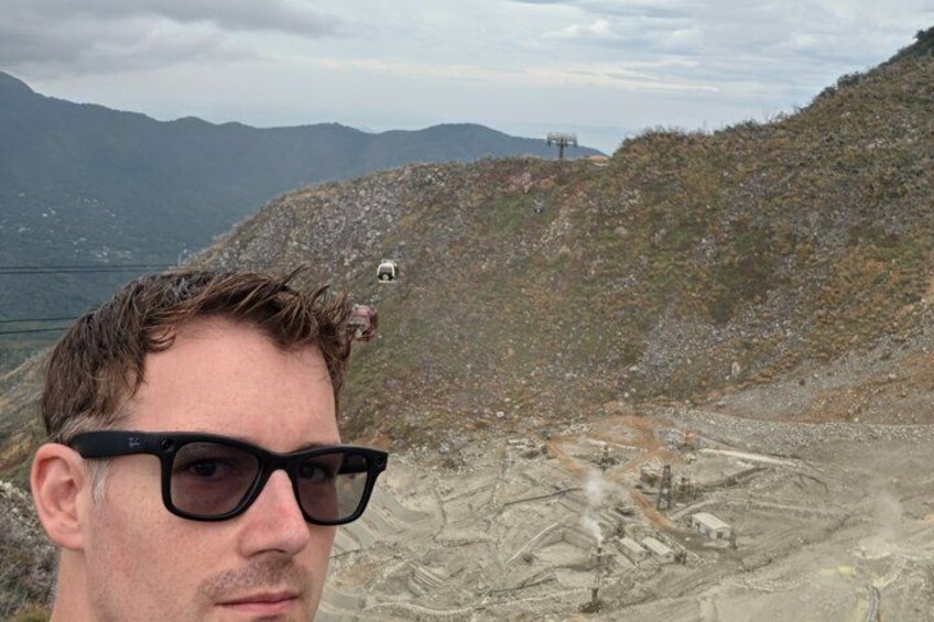 A person standing on a rocky hillside with a view of a distant landscape. 2