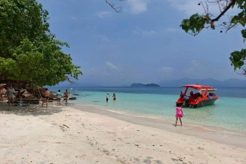 A beach with clear turquoise water, a red boat, and people near the shore. 5