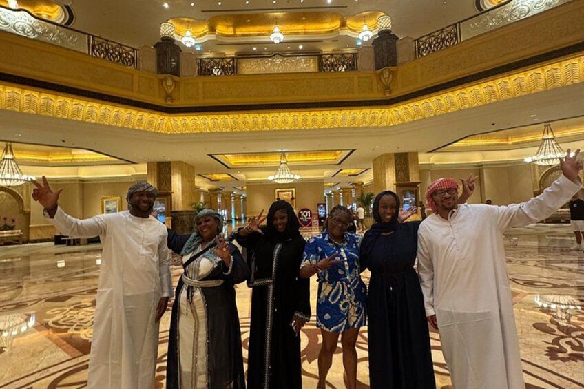 A group of people in a grand, ornate lobby with chandeliers and a high ceiling. 4