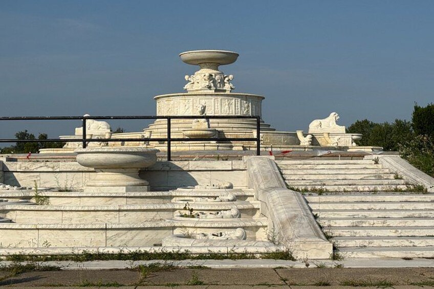 A large, ornate fountain with steps leading up to it, surrounded by a fence. 1