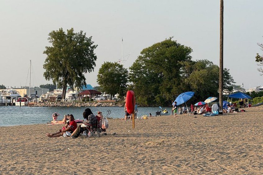 A beach with people sunbathing, umbrellas, and boats in the background. 4