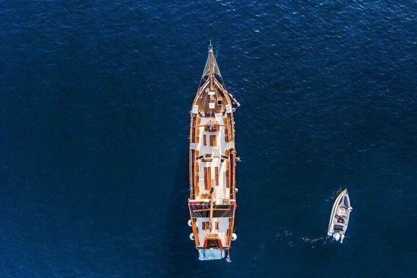 A large ship with a pointed bow and a smaller boat nearby. 3