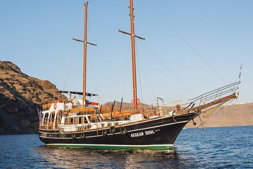 A sailing boat named 'AEGEAN SOUL' on calm waters with a rocky shoreline in the background. 5