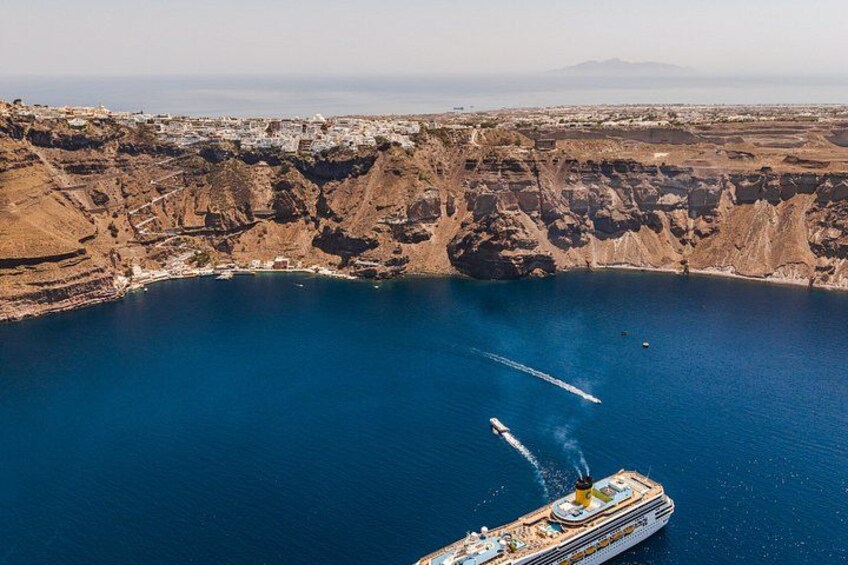 A cruise ship in a large body of water surrounded by rocky cliffs. 2