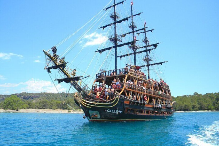 A large, multi-deck sailing ship with passengers on deck, sailing on a clear blue sea. 1