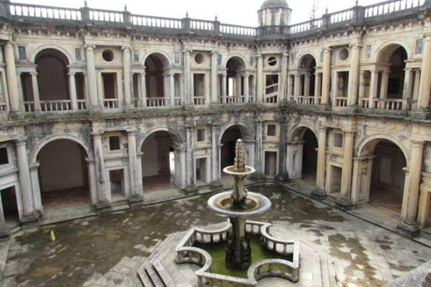 An ancient courtyard with a central fountain, surrounded by arches and columns. 2