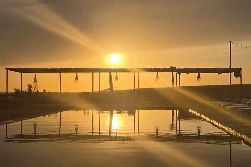 A sunset over a calm body of water with a bridge and distant structures. 5
