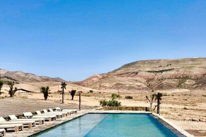 A pool with lounge chairs, surrounded by desert hills. 1
